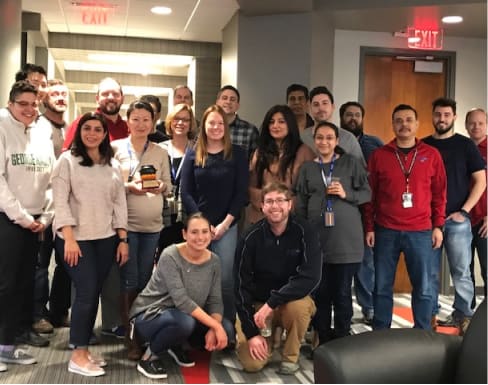 A group photo of CTAC employees standing and smiling in their office lobby