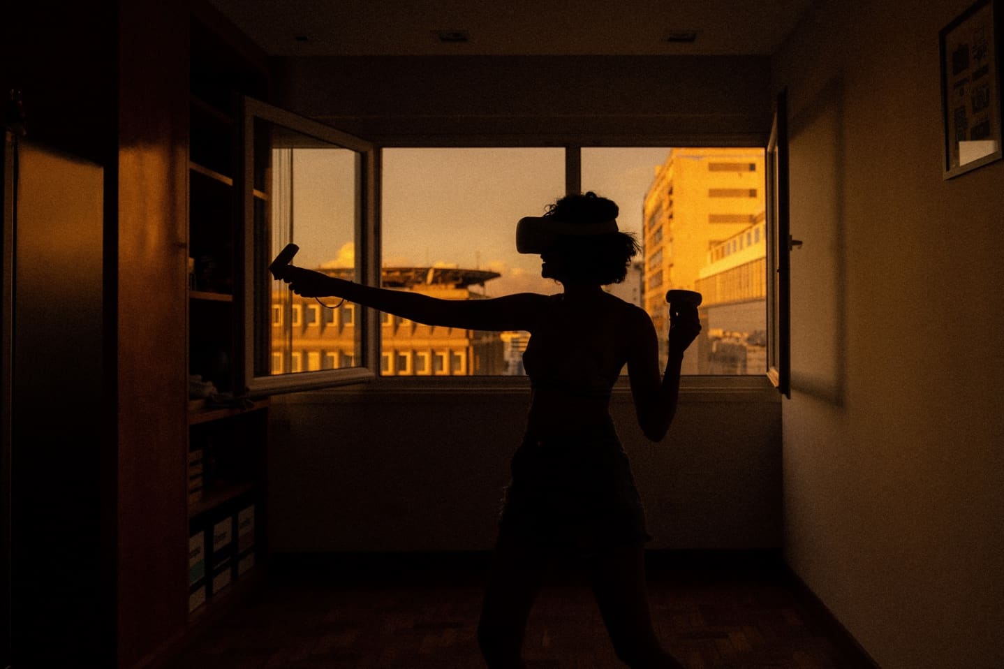 A young woman in her apartment playing a virtual game on a VR headset