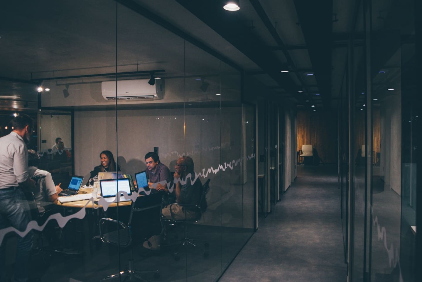 A group of employees in a meeting with their laptops sitting around a conference table